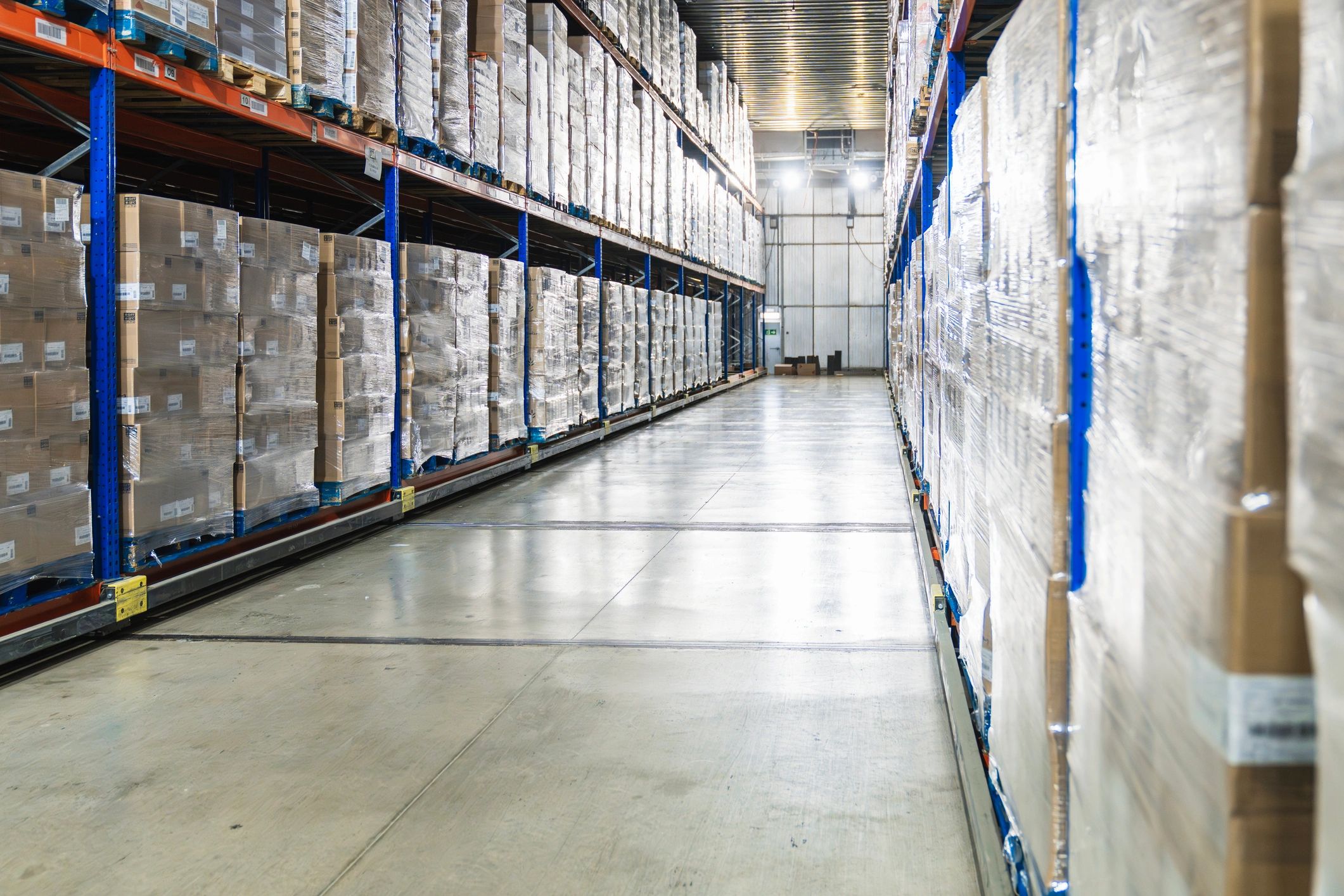 Pallets of wrapped boxes in a cold storage logistics warehouse aisle