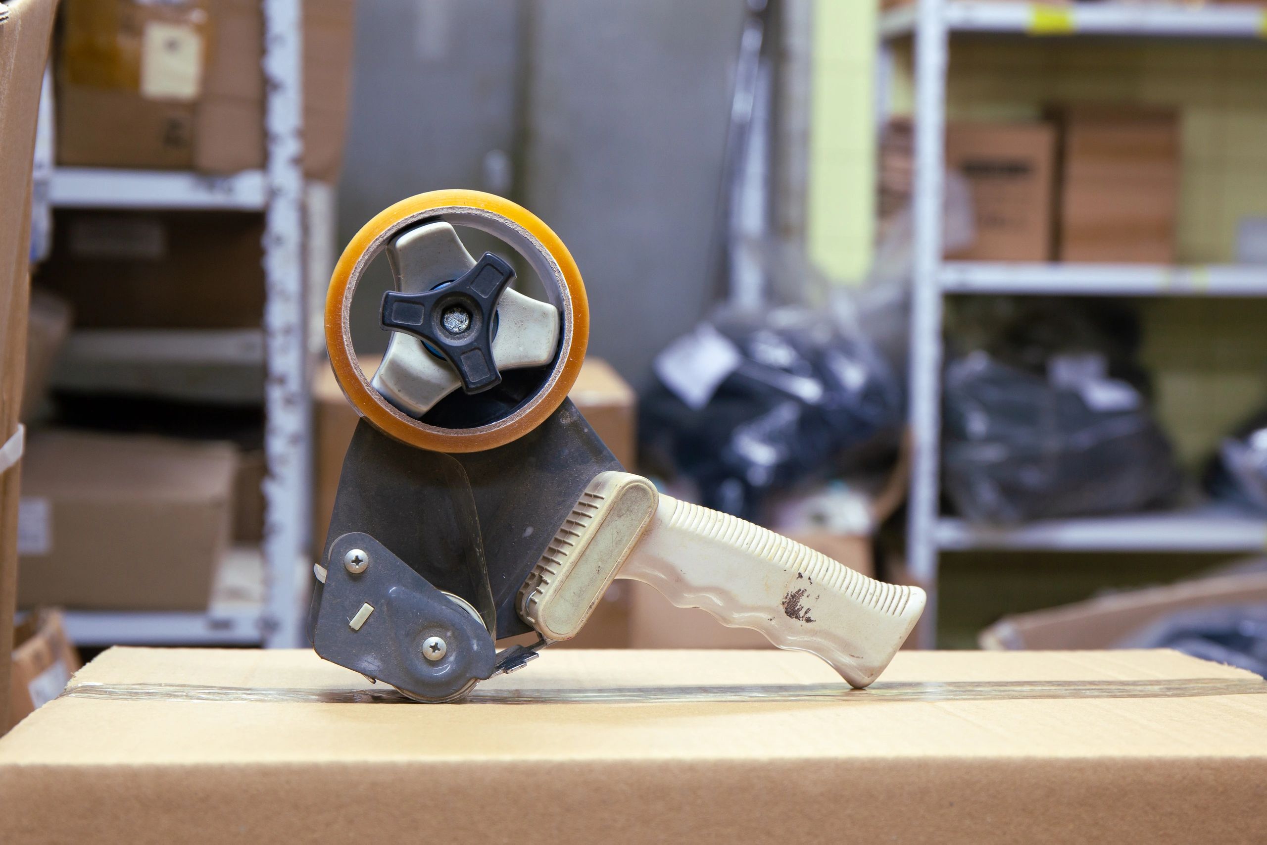 Tape dispenser applying packaging tape to a cardboard box