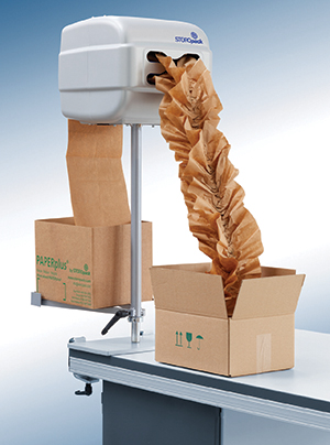 Industrial paper packaging machine dispensing kraft paper into cardboard boxes